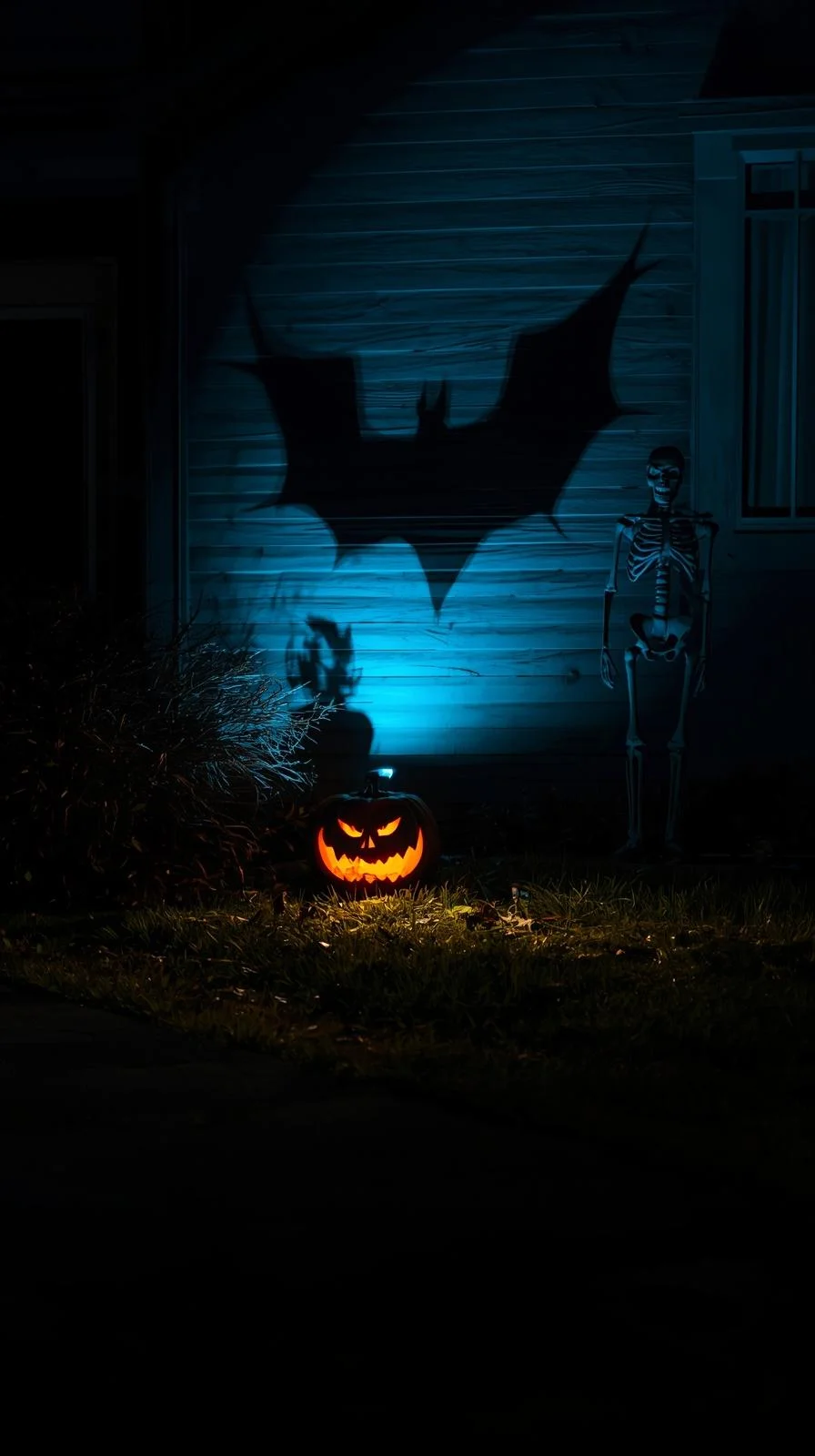 Halloween yard with bat shadows, glowing pumpkin, and skeleton, showing outdoor Halloween decorations ideas with light.
