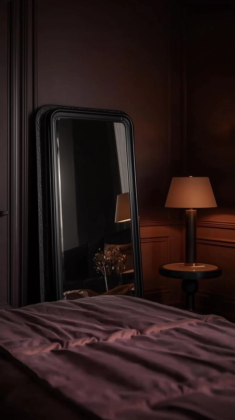 Dark feminine aesthetic bedroom with antique-framed mirror and brass accents reflecting soft warm light across dark-toned walls.
